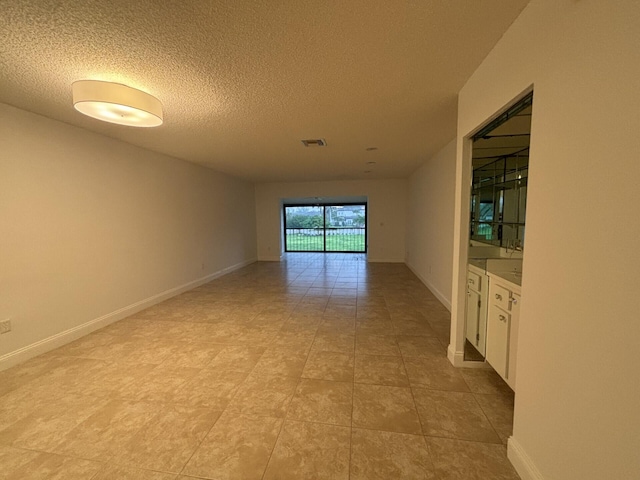 spare room featuring a textured ceiling and light tile patterned flooring