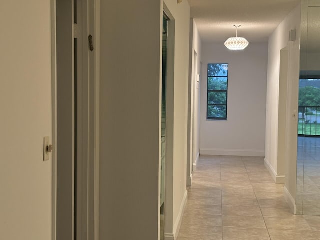 hall with a textured ceiling and light tile patterned floors