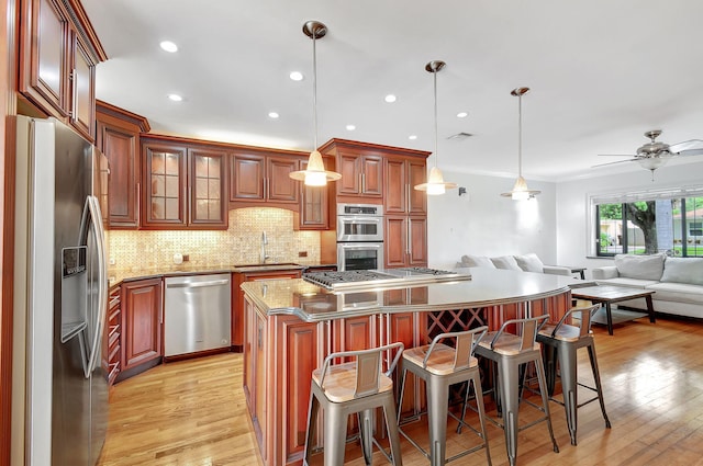 504 51st St, West Palm Beach, FL 33407 - kitchen featuring stainless steel appliances, a sink, open floor plan, decorative backsplash, and light wood-style floors