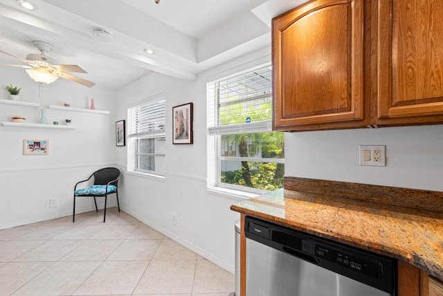 kitchen with ceiling fan, dark stone countertops, light tile patterned flooring, and stainless steel dishwasher