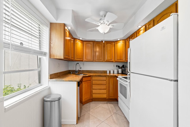 kitchen with white appliances, light tile patterned floors, sink, ceiling fan, and light stone counters