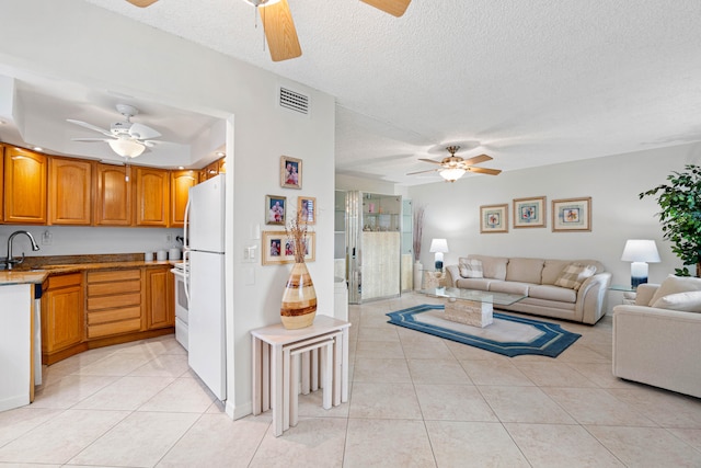 interior space featuring a textured ceiling, ceiling fan, sink, and light tile patterned flooring