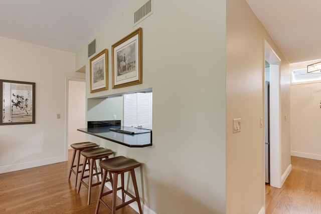 kitchen with a kitchen breakfast bar and light hardwood / wood-style flooring