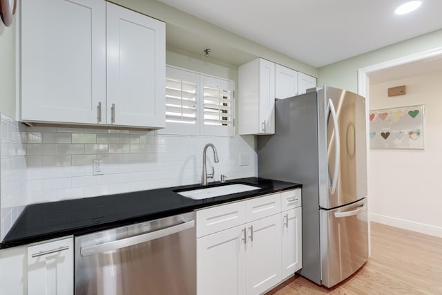 kitchen with light hardwood / wood-style flooring, appliances with stainless steel finishes, white cabinetry, sink, and decorative backsplash