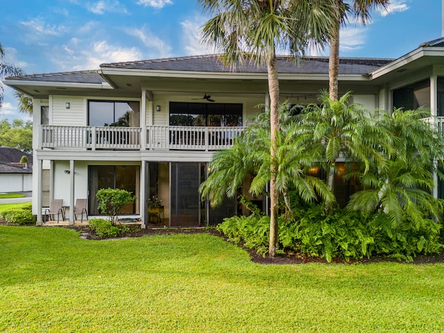 back of house featuring a balcony, a lawn, and ceiling fan