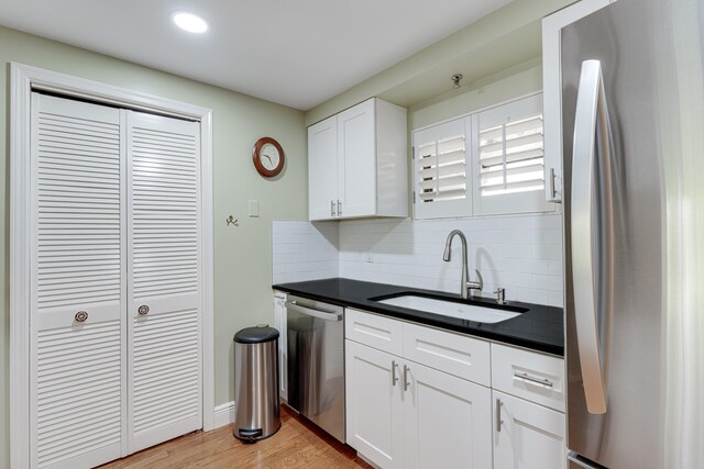 kitchen featuring stainless steel appliances, sink, light wood-type flooring, and white cabinetry