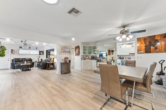 dining space with a textured ceiling, ceiling fan, and light hardwood / wood-style floors