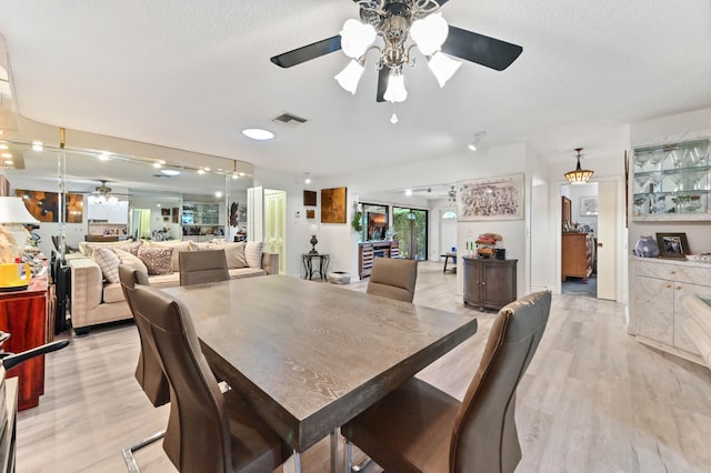 dining room featuring a textured ceiling, ceiling fan, and light wood-type flooring