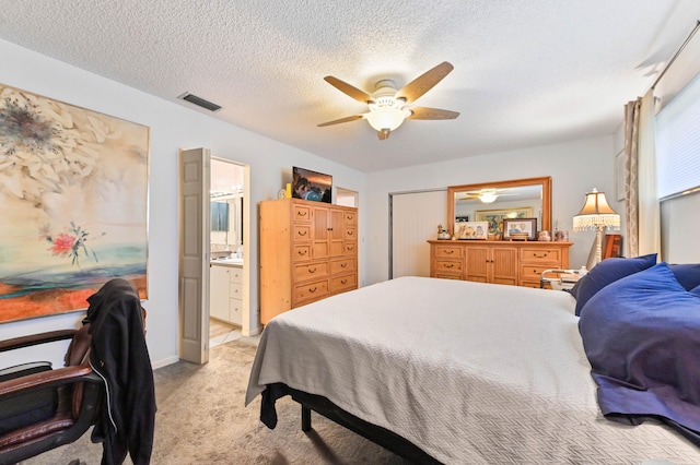 bedroom with light colored carpet, a textured ceiling, ensuite bathroom, and ceiling fan