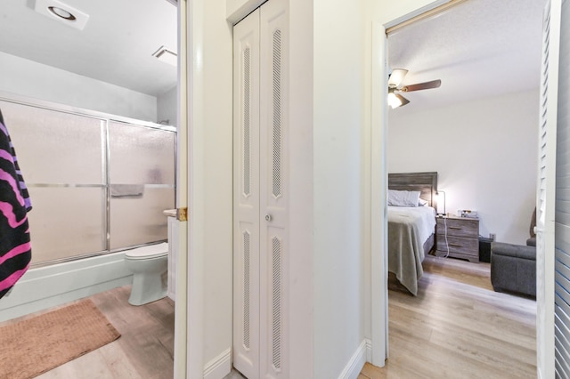 bathroom featuring ceiling fan, an enclosed shower, wood-type flooring, and toilet