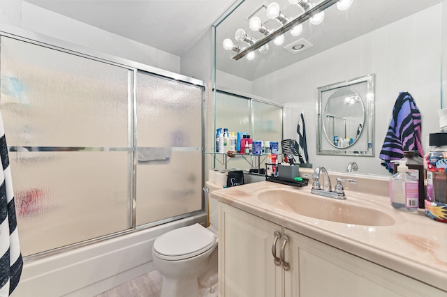 full bathroom featuring toilet, hardwood / wood-style flooring, bath / shower combo with glass door, and vanity