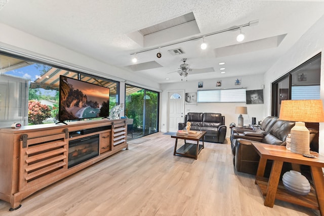 living room with track lighting, a textured ceiling, light hardwood / wood-style flooring, and ceiling fan