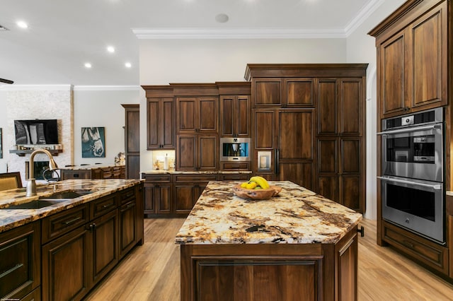 kitchen with sink, stainless steel appliances, a center island, crown molding, and light hardwood / wood-style floors