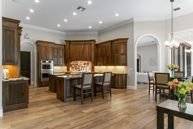 11780 Otter Run, Lake Worth, FL 33449 - kitchen with a kitchen breakfast bar, a center island with sink, recessed lighting, stainless steel double oven, and arched walkways