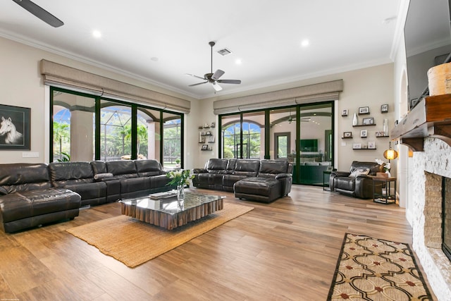 living room with ceiling fan, light hardwood / wood-style floors, a fireplace, and ornamental molding