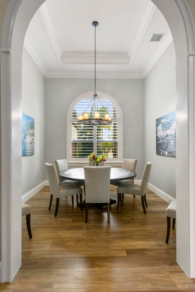 dining room with ornamental molding, a raised ceiling, a chandelier, and hardwood / wood-style floors