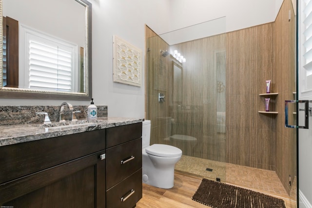 bathroom featuring hardwood / wood-style floors, vanity, toilet, and a shower with door