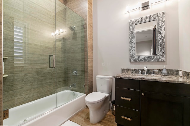 full bathroom with hardwood / wood-style floors, bath / shower combo with glass door, toilet, and vanity