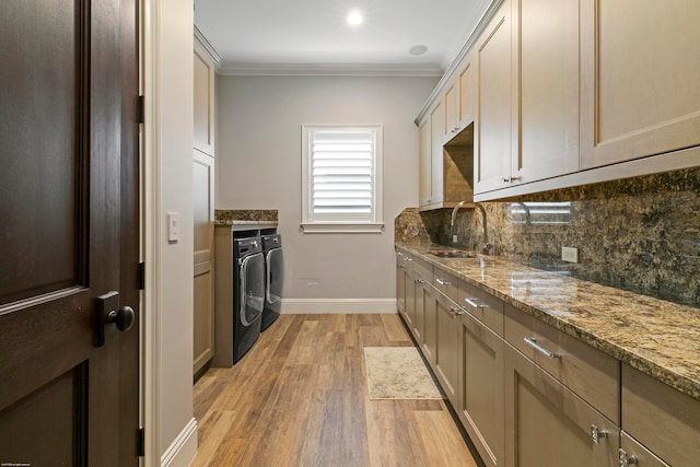 kitchen with ornamental molding, sink, light hardwood / wood-style flooring, stone counters, and independent washer and dryer