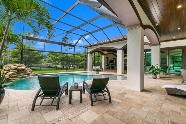 view of pool featuring glass enclosure and a patio area