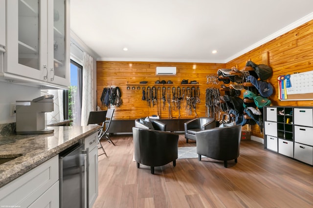 interior space featuring ornamental molding, light wood-type flooring, wood walls, and a wall unit AC