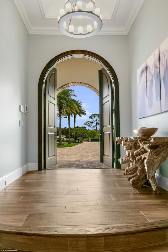 entrance foyer featuring a notable chandelier, ornamental molding, and hardwood / wood-style floors