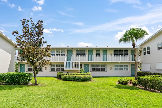 rear view of property with a yard and a balcony