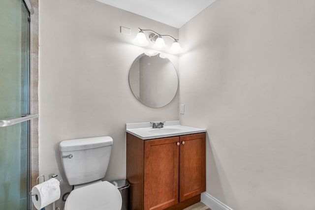 bathroom with a shower with shower door, toilet, and vanity