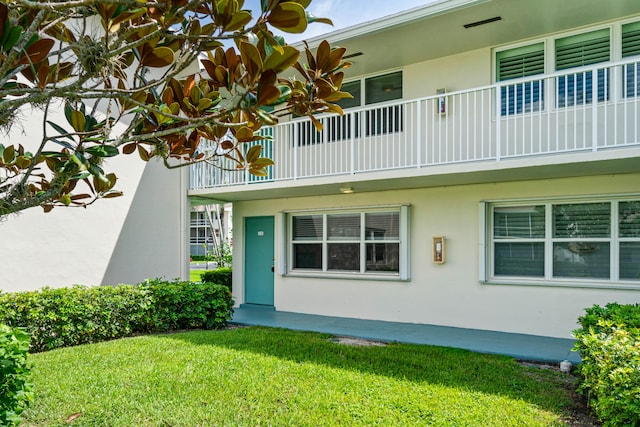 property entrance featuring a balcony and a yard