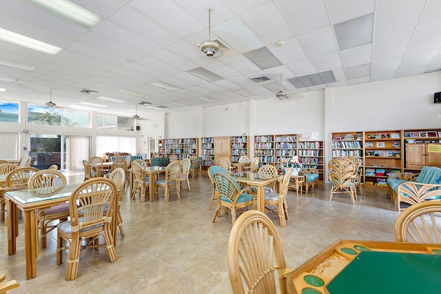 tiled dining area with ceiling fan and a drop ceiling