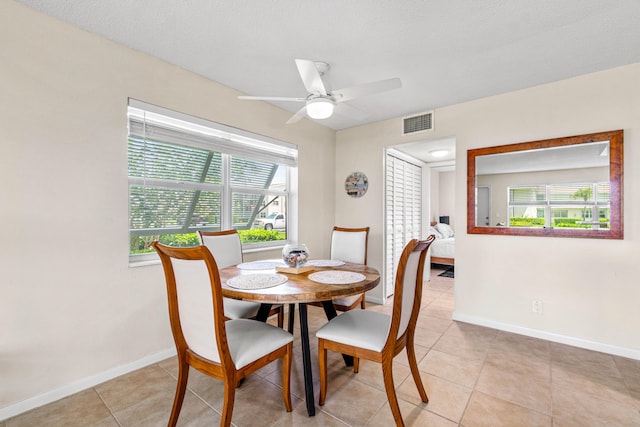 dining area featuring ceiling fan, a textured ceiling, light tile patterned flooring, and a healthy amount of sunlight