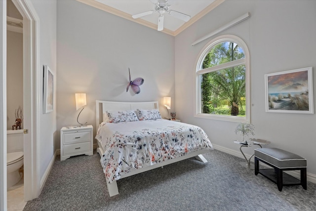 bedroom featuring ceiling fan, ornamental molding, ensuite bathroom, and dark colored carpet