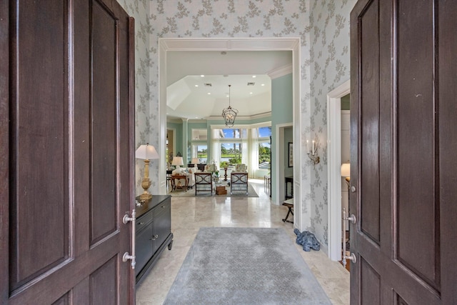 entrance foyer with crown molding and a chandelier