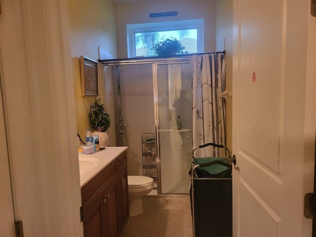 bathroom featuring tile patterned flooring, vanity, toilet, and a shower with shower door