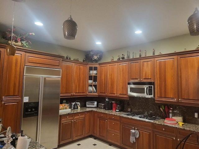 kitchen with light stone countertops, decorative backsplash, stainless steel appliances, and decorative light fixtures