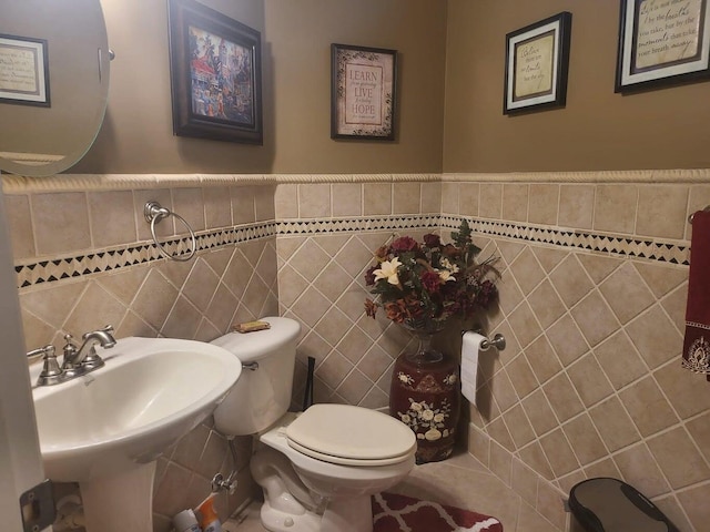 bathroom featuring sink, toilet, and tile walls