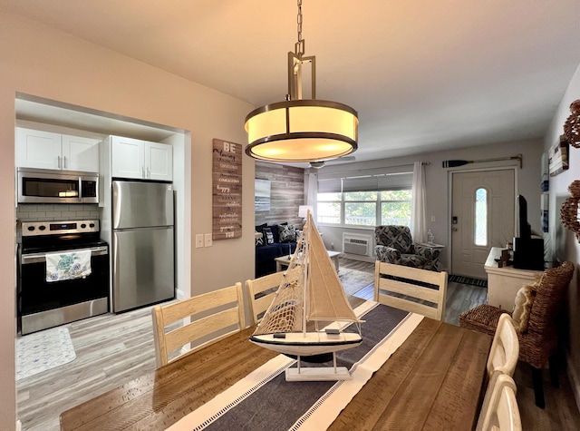 dining room featuring light wood-type flooring and a wall unit AC