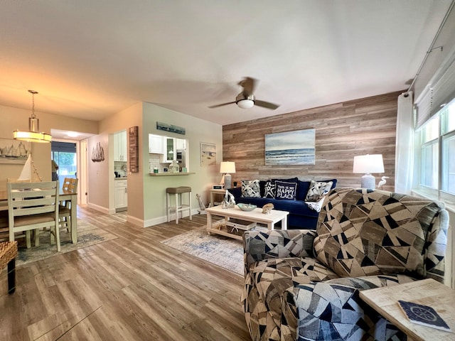 living room featuring ceiling fan, wood walls, and hardwood / wood-style floors