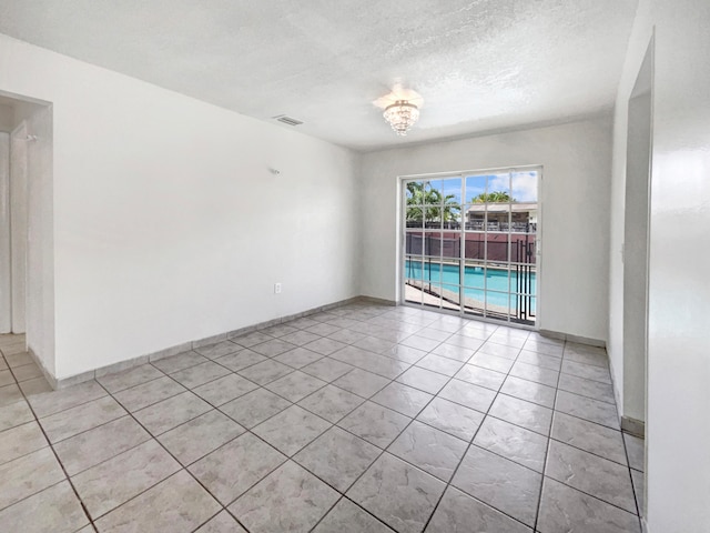 tiled empty room featuring a textured ceiling