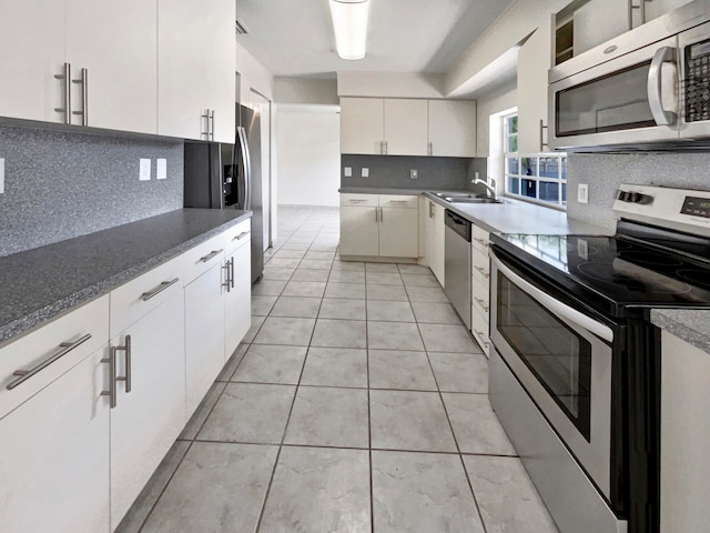 kitchen featuring backsplash, appliances with stainless steel finishes, white cabinetry, sink, and light tile patterned flooring