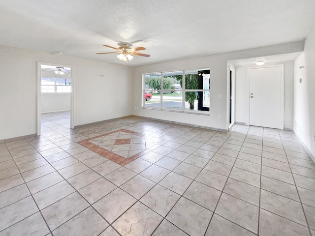 spare room with a textured ceiling, light tile patterned flooring, and ceiling fan