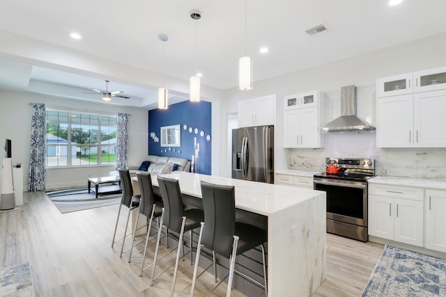 kitchen with wall chimney range hood, appliances with stainless steel finishes, and white cabinetry