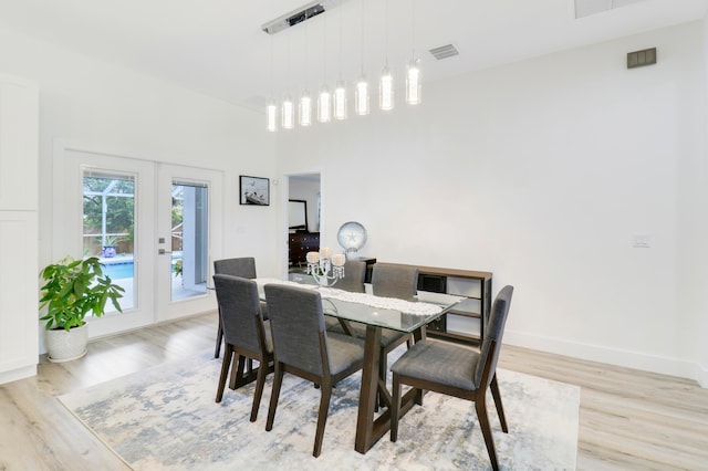 dining space with french doors and light hardwood / wood-style flooring