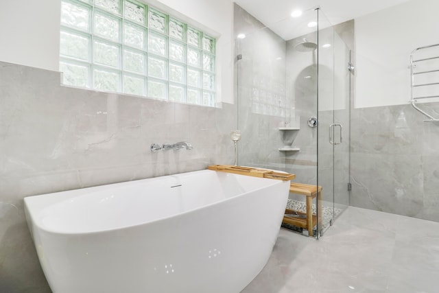 bathroom featuring tile walls and separate shower and tub