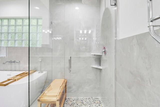 bathroom with tile walls and separate shower and tub