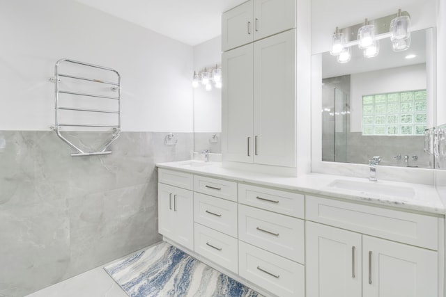 bathroom with tile patterned flooring, vanity, tiled shower, radiator, and tile walls