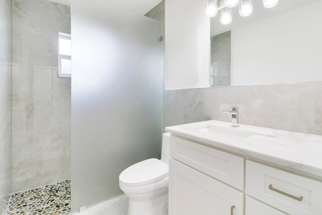 bathroom featuring tiled shower, vanity, and toilet