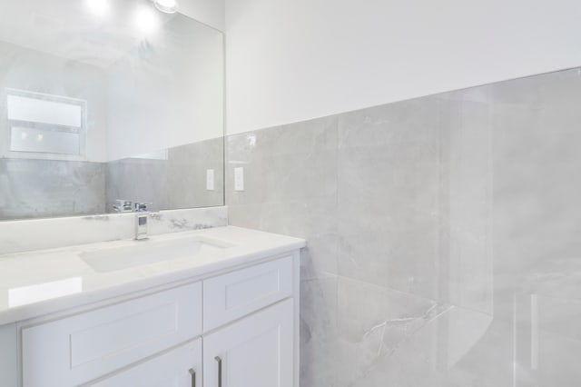 bathroom with vanity and tile walls