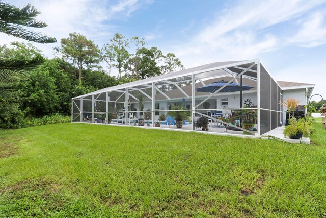 back of property with a lanai and a lawn