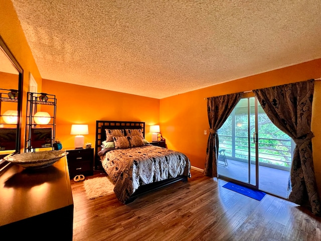 bedroom with a textured ceiling, hardwood / wood-style flooring, and access to exterior